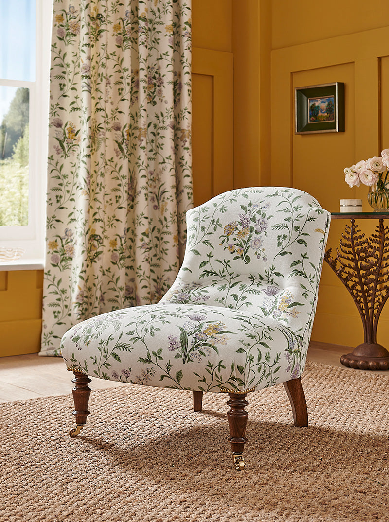 Nina Campbell Munro Chair, in a white, green, yellow and lilac floral fabric, on a white background.