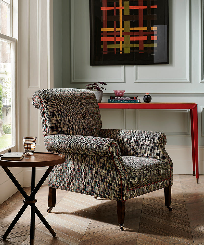 Nina Campbell Robert Browning Armchair, in a brown fabric with red piping, Photographed alongside the Nina Campbell Button Table.