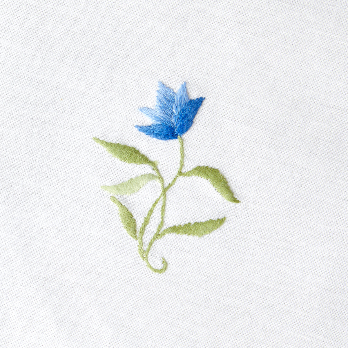 Close up of Nina Campbell cocktail / coaster blue flower on a white background