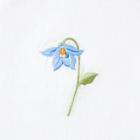 Close up of Nina Campbell cocktail / coaster blue flower on a white background