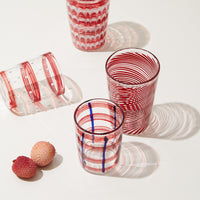 Nina Campbell Red Pinstripe Swirl against a white background with other red glassware